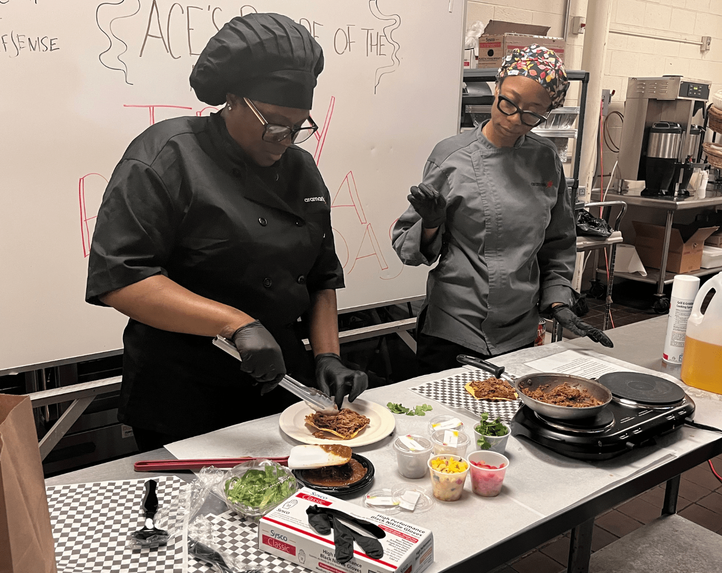 Two chefs hosting a cooking demonstration for students.
